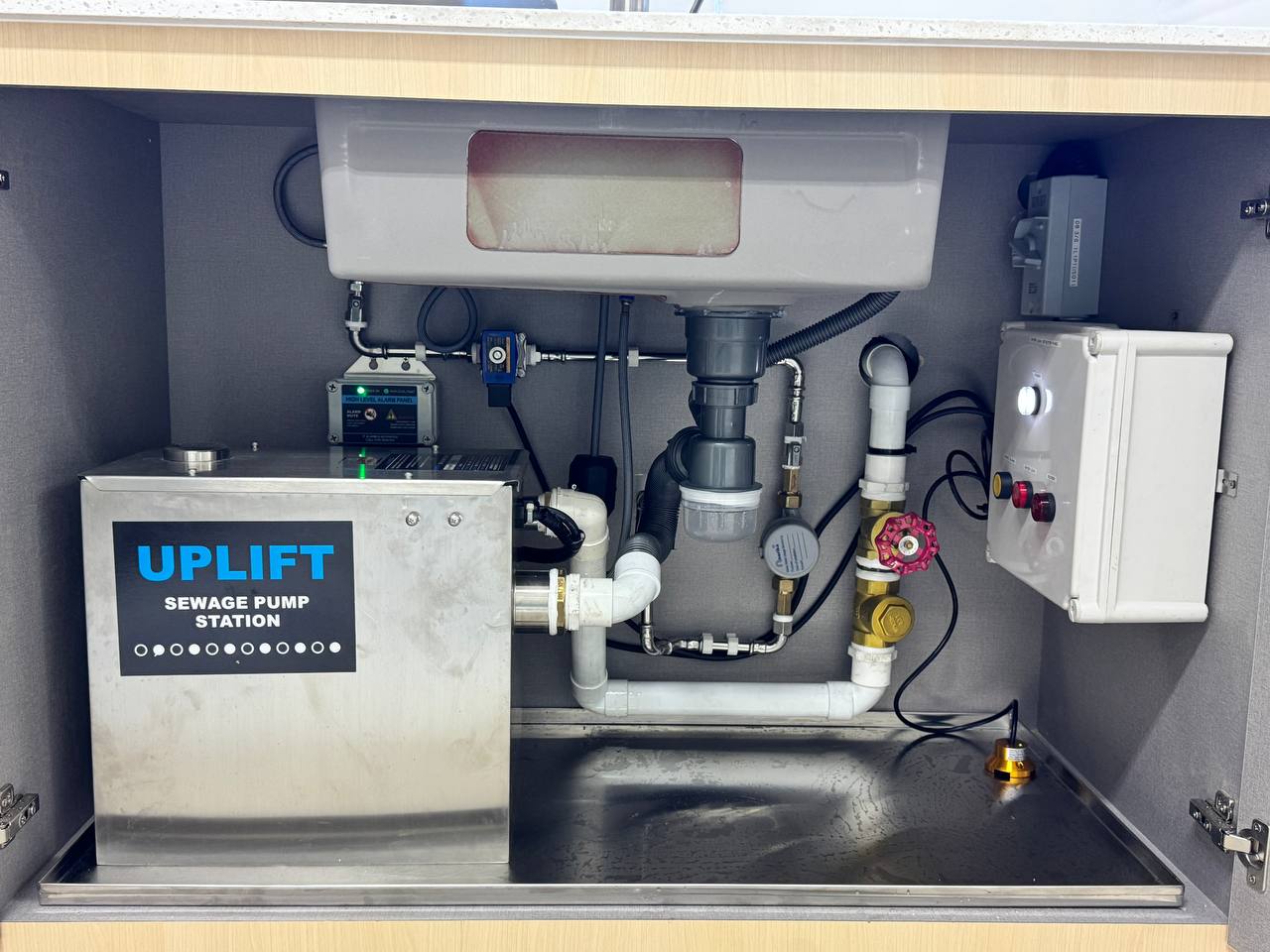 UPLIFT stainless steel sewage pump station with control panel installed under a pantry sink in Singapore